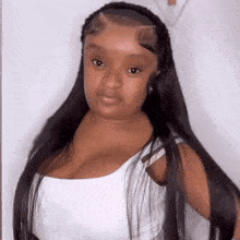 a woman with long black hair is wearing a white tank top and a headband .