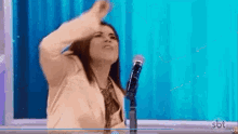 a woman is standing in front of a microphone and dancing .