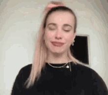 a woman with pink hair is making a funny face with her eyes closed .