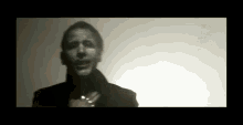 a man with a necklace around his neck is standing in a dark room