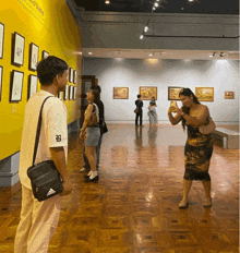 a woman taking a picture in a museum with a yellow wall that says art of filipinos