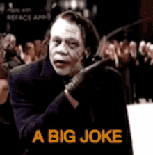 a man in a suit and gloves says a big joke in front of a crowd