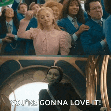 a woman in a pink dress is standing in front of a group of people and says `` you 're gonna love it '' .