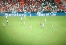a group of soccer players are playing on a field with a banner for allianz in the background