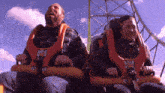 a man and a woman are riding a roller coaster with the letter g on the front