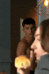 a man without a shirt is standing next to a woman who is eating a bun