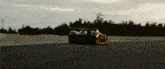 a black sports car is driving down a road with a sunset in the background
