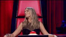 a woman in a black dress sits in a chair with a red button