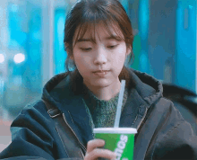 a woman is drinking from a green cup that says sonic