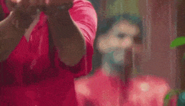a woman in a red shirt is standing in front of a mirror and looking at herself .