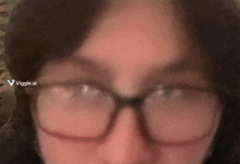 a close up of a person wearing glasses with a viggle ai logo in the corner .