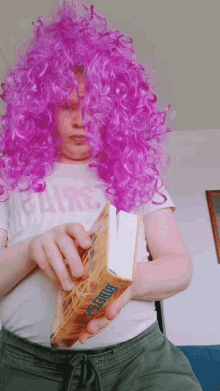 a person wearing a purple wig is holding a book called bible