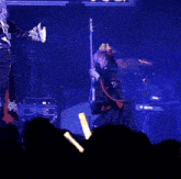 a woman in a black dress is dancing on a stage with a guitar