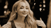 a woman with blonde hair and a necklace smiles for the camera