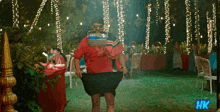 a man in a red shirt is standing in front of a table with hk written on it