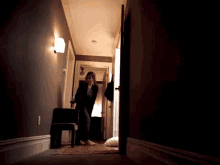 a woman is standing in a hallway talking on a cell phone
