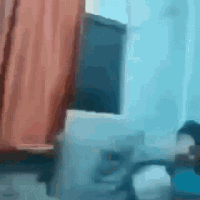 a blurry picture of a person sitting in a chair in front of a window in a room .