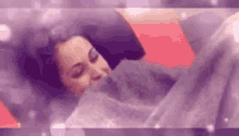 a woman is sleeping in a bed with a blanket on her head .