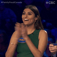 a woman applauds while wearing a green tank top that says mina