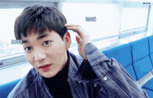 a young man is sitting on a blue couch and touching his head