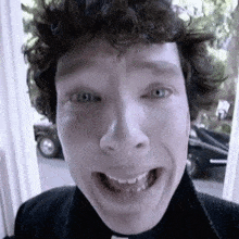 a man with curly hair is making a funny face with his mouth wide open .