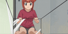 a girl in a red shirt is sitting in a glass container