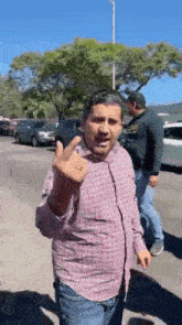 a man wearing a plaid shirt is giving the middle finger