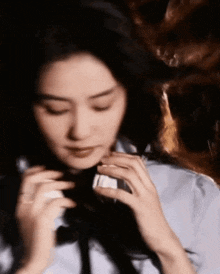 a woman in a blue shirt and black tie is holding a bottle of perfume .