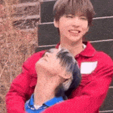 a man in a red jacket is hugging another man .