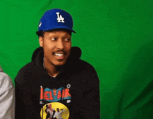 a man wearing a la dodgers hat and a black hoodie