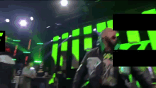 a blurry picture of a man standing in front of a green screen with the letter e on it