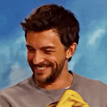 a man with a beard is smiling and holding a banana