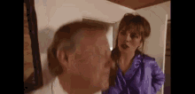 a woman in a purple robe is standing next to a man in a white shirt and talking to him .