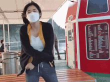 a woman wearing a face mask stands in front of a red and white building