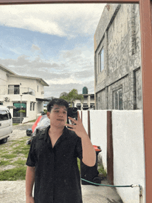 a man in a black shirt takes a selfie in front of a mirror