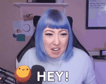 a woman with blue hair says hey while sitting in a chair