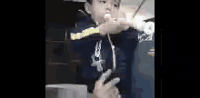 a young boy is holding a marshmallow in his hand and making a peace sign with his hands .