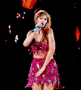 a woman singing into a microphone in a pink dress