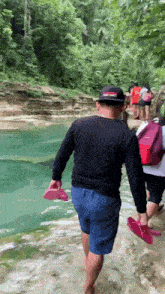 a man in a black shirt and blue shorts is walking through the water