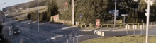a car is driving down a street with a fence in the foreground