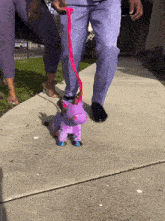 a person in purple pants is walking a stuffed unicorn