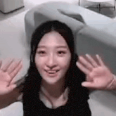 a woman is sitting on a couch with her hands up and smiling .