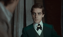 a man in a green suit is looking at himself in the mirror .