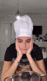 a woman wearing a chef 's hat is holding her head