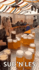 a woman is sitting at a table with a bunch of beer mugs on it .