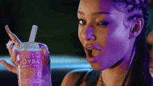 a woman holds a cup of joyba bubble tea with a straw