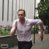 a man in a white shirt and black pants is running down a sidewalk with an amazon prime arrow in the corner