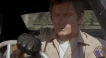 a man in a sheriff 's uniform is driving a car .