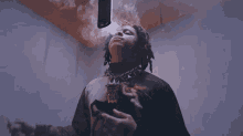 a man with dreadlocks is smoking a cigarette with smoke coming out of his mouth .