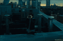 a person looking through binoculars on a rooftop with a #godzillamovie watermark